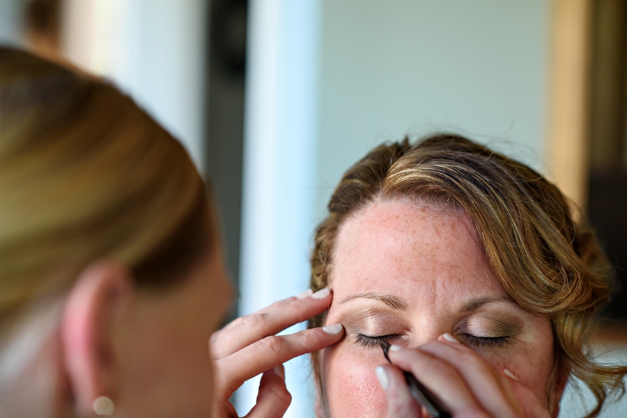 A bride getting her makeup done on her wedding day.